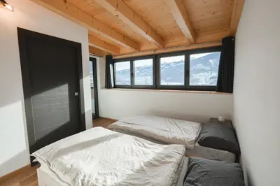 two beds in a room with a window at MOUNTAIN DELUXE 27 APARTMENTS con WELLNESS in Cavalese