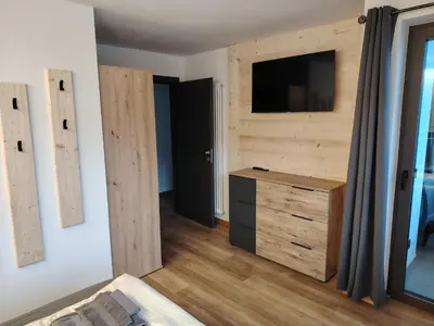 a bedroom with a wooden wall with a tv and a dresser at MOUNTAIN DELUXE 27 APARTMENTS con WELLNESS in Cavalese