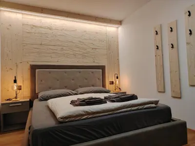 a bedroom with a large bed with a headboard at MOUNTAIN DELUXE 27 APARTMENTS con WELLNESS in Cavalese