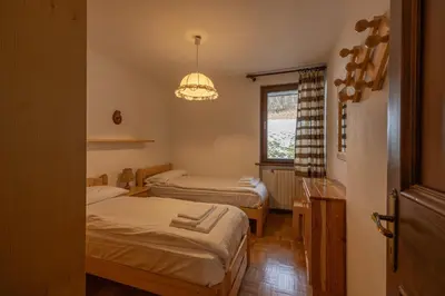 a room with two beds and a window and a chandelier at Casa alla Sorgente, con vista panoramica in San Vito di Cadore