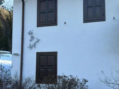 a white building with two windows and a door at Casa alla Sorgente, con vista panoramica in San Vito di Cadore