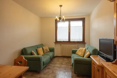 a living room with two green couches and a television at Casa alla Sorgente, con vista panoramica in San Vito di Cadore