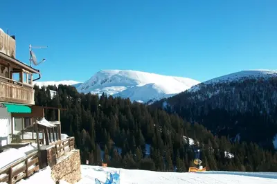 a person sitting on a snow covered slope with a mountain at Verweilen auf Meran 2000 in Avelengo