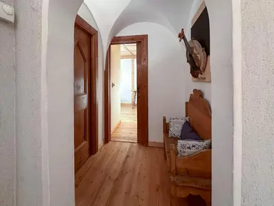 a hallway with an open door and a wooden floor at Ciasa De Doni in Pozza di Fassa