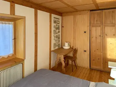 a bedroom with a bed and a table and a window at Ciasa De Doni in Pozza di Fassa