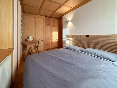 a bedroom with a blue bed with a wooden headboard at Ciasa De Doni in Pozza di Fassa