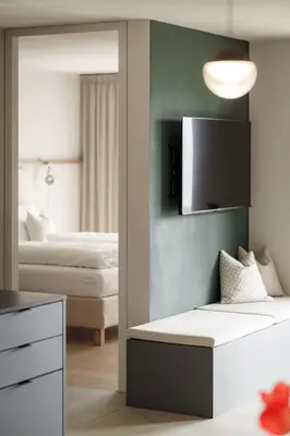 a bedroom with two beds and a tv on the wall at Nikolausberg - Hof im Garten in Caldaro