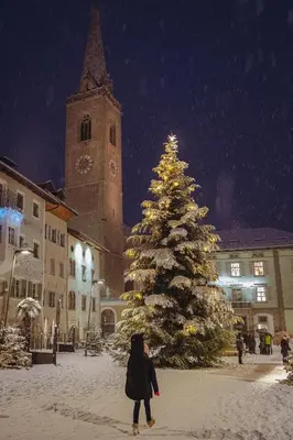 a woman walking past a christmas tree in the snow at Nikolausberg - Hof im Garten in Caldaro