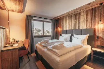 a bedroom with a bed and a desk and a window at Hotel Piz Seteur in Selva di Val Gardena