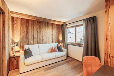 a living room with a white couch and a window at Hotel Piz Seteur in Selva di Val Gardena