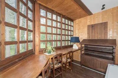 a large room with a wooden table and windows at B&B Villa La Bercia in San Vigilio Di Marebbe