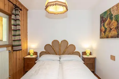 a bedroom with a large white bed with two lamps at B&B Villa La Bercia in San Vigilio Di Marebbe