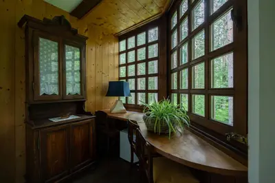 a home office with a table and windows at B&B Villa La Bercia in San Vigilio Di Marebbe