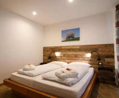 a bedroom with a large white bed with towels at Abete rosso in Tesero