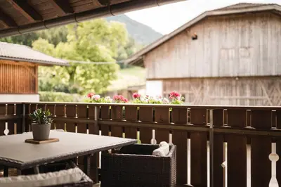 a balcony with two chairs and a table with a vase on it at Oberhuberhof in Rodengo