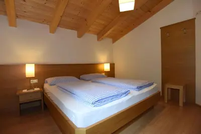a bedroom with a large bed with a wooden headboard at Haus Waldruhe in Villandro