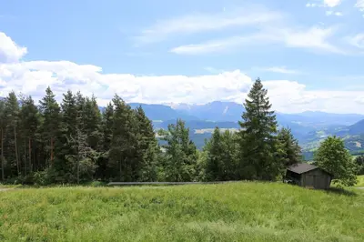 a grassy hill with a smallshed on the side of a mountain at Haus Waldruhe in Villandro