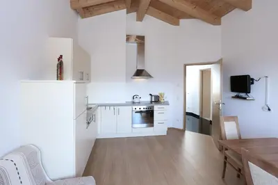 a kitchen and dining room with white walls and wooden floors at Haus Waldruhe in Villandro