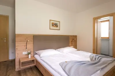 a bedroom with a large bed with a wooden headboard at B&B Garni Schorneck in Brunico