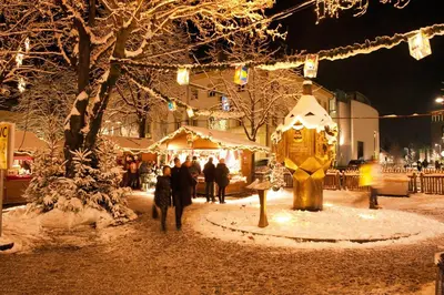 a group of people walking around a christmas market at night at B&B Garni Schorneck in Brunico