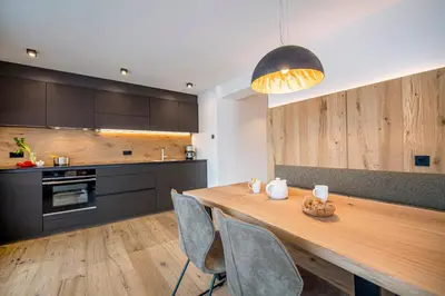 a kitchen with a wooden table with chairs and aendant light at apartment allium in Selva di Val Gardena