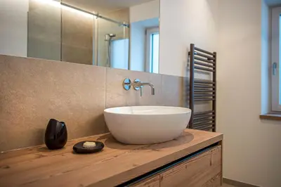 a bathroom with a white bowl sink on a wooden counter at apartment allium in Selva di Val Gardena