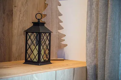 a black lantern sitting on a shelf next to a curtain at apartment allium in Selva di Val Gardena