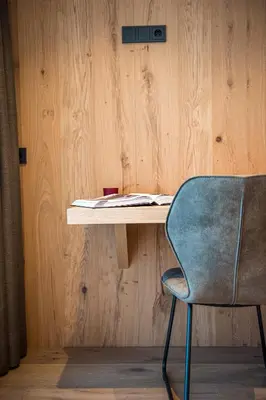 a desk with a chair next to a wooden wall at apartment allium in Selva di Val Gardena