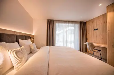 a hotel room with a large bed and a chair at apartment allium in Selva di Val Gardena