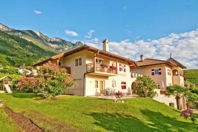 a large house on a hill with a green yard at Leuchtenhof in Caldaro