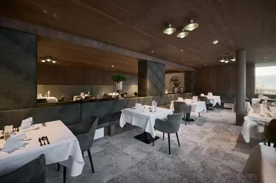 a restaurant with white tables and chairs and a counter at Berghotel in Racines