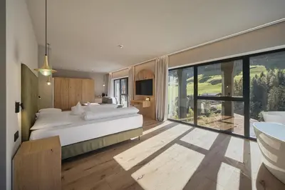 a bedroom with a large bed and a balcony at Berghotel in Racines