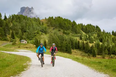 two people riding bikes down a dirt road at Naturae Lodge Wellness & Spa in Alleghe