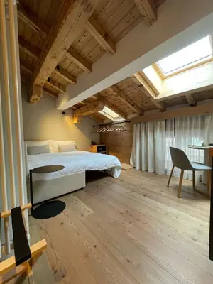 a bedroom with a bed and a desk and a chair at Naturae Lodge Wellness & Spa in Alleghe