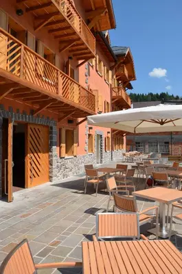 an outdoor patio with tables and chairs and umbrellas at Lumen in Falcade