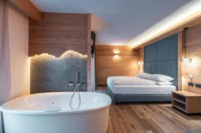 a bathroom with a tub and a bedroom with a bed at Dolomiti Luxury Mountain View SKI-IN SKI-OUT in Canazei