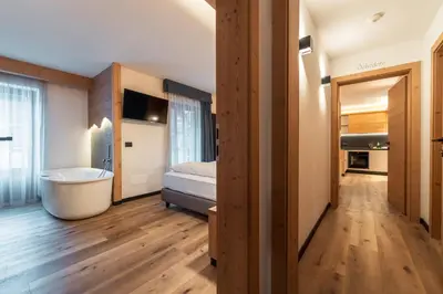 a bathroom with a tub and a bed in a room at Dolomiti Luxury Mountain View SKI-IN SKI-OUT in Canazei