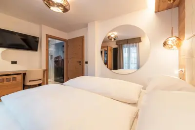 a bedroom with two white beds and a mirror at Dolomiti Luxury Mountain View SKI-IN SKI-OUT in Canazei