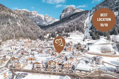 a city covered in snow with the text best location at Dolomiti Luxury Mountain View SKI-IN SKI-OUT in Canazei