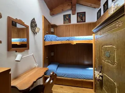 a small room with two bunk beds and a desk at Mansarda a Cortina in Cortina dʼAmpezzo