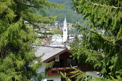 a view of a town through the trees at Mansarda a Cortina in Cortina dʼAmpezzo
