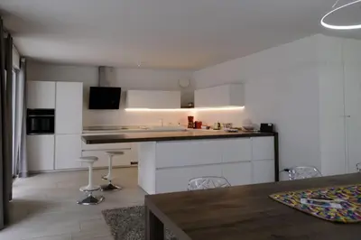 a kitchen with white cabinets and a table and chairs at SWEETHOME MUSEO - con Garage in Bolzano