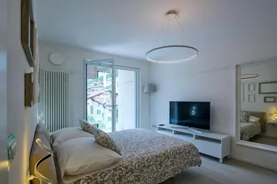 a white bedroom with a bed and a television at SWEETHOME MUSEO - con Garage in Bolzano