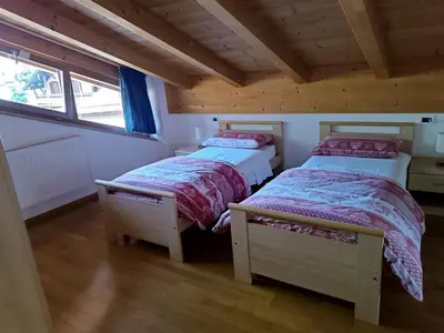 two beds in a small room with wooden ceilings at Appartamento Diobono in San Lugano