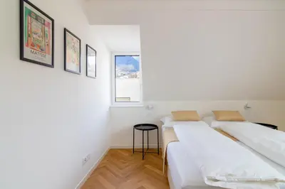 two beds in a room with two windows at Villa Bregenz Apartment in Merano