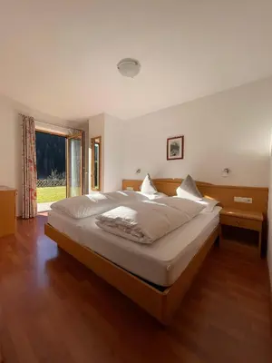 a bedroom with a large bed and a large window at Appartamenti Hetty in Santa Cristina in Val Gardena