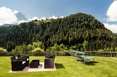 a patio with chairs and a table and a mountain at Appartamenti Hetty in Santa Cristina in Val Gardena