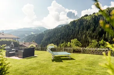 a bench in a yard with a view of a mountain at Appartamenti Hetty in Santa Cristina in Val Gardena
