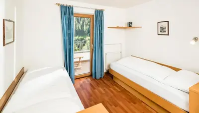 a bedroom with two beds and a window at Appartamenti Hetty in Santa Cristina in Val Gardena