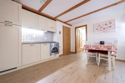 a kitchen with white cabinets and a table at Cesa alla Cascata in Canazei